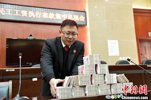 北川法院为农民工讨薪 145万工资集中兑付。图为执法人员正在清点成捆的钞票。<a target=