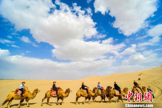 图为游客骑骆驼在鸣沙山观赏大漠风光。 王斌银 摄 图为游客骑骆驼在鸣沙山观赏大漠风光。 王斌银 摄