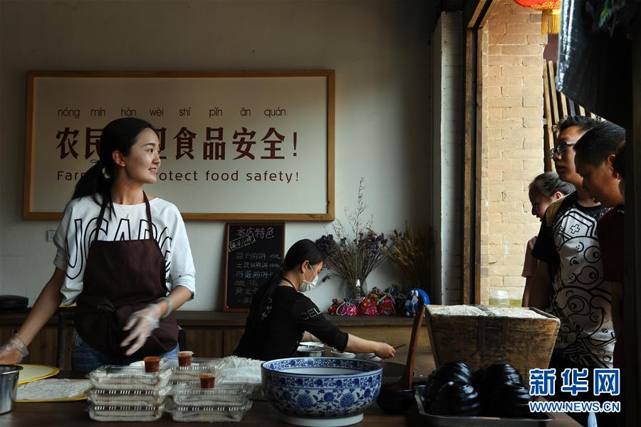 5月1日，礼泉县袁家村陕北小吃店的店主李蓉（左一）为顾客现场制作长子煎饼。
